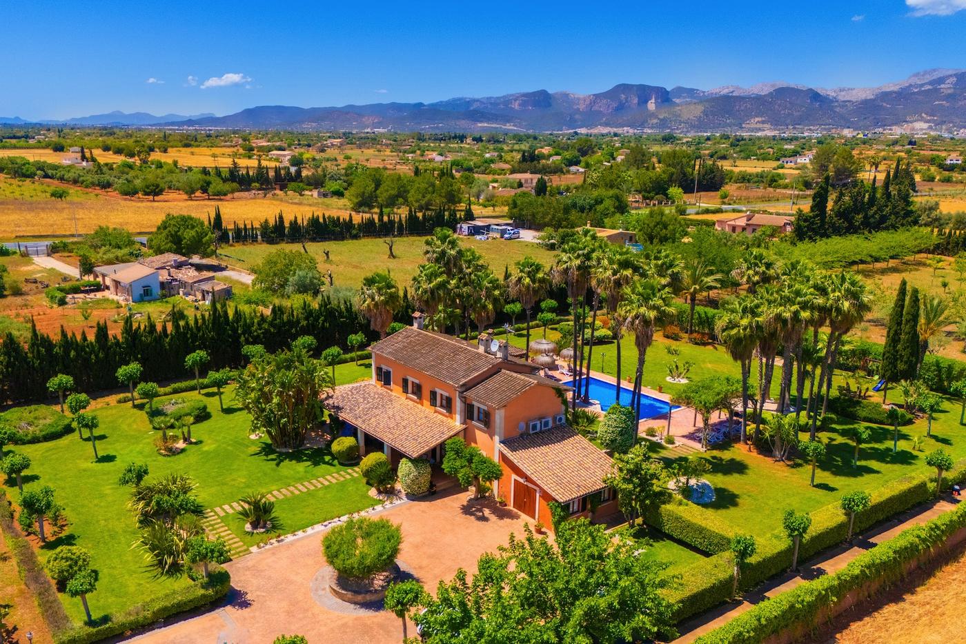 Aerial view of Finca Mil Flores with palm garden, pool and the Tramuntana mountains
